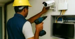 A technician in a safety helmet installing a CCTV camera